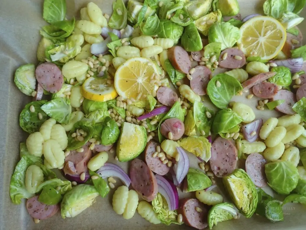 brussels sprouts gnocchi lemon pine nuts and red onion on a sheet pan lined with parchment paper