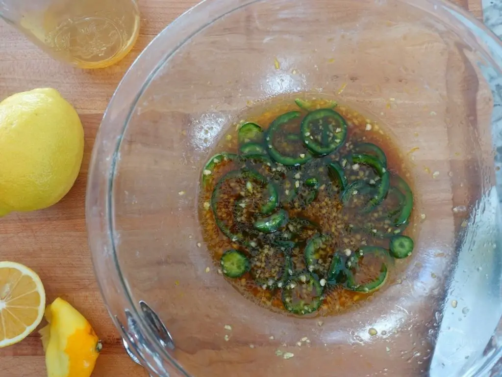 honey jalapeno marinade in a glass bowl with lemons on the side