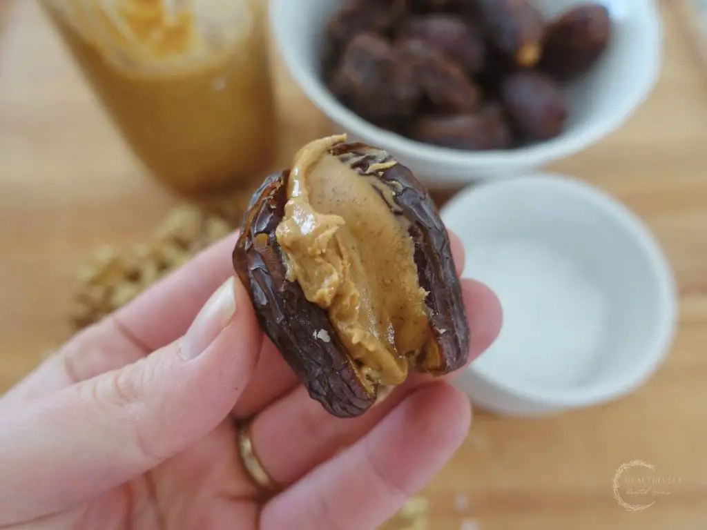 date stuffed with peanut butter with a bowl of dates and another bowl of sea salt in the background