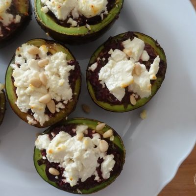 roasted avocados stuffed with goat cheese and kalamata olive tapenade on a white plate