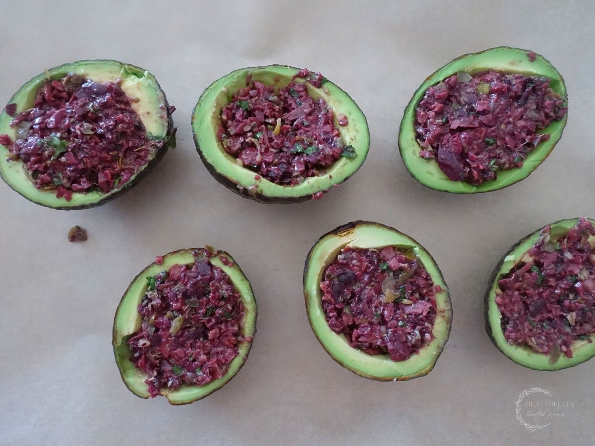 parchment lined baking sheet lined with avocados filled with kalamata olive tapenade