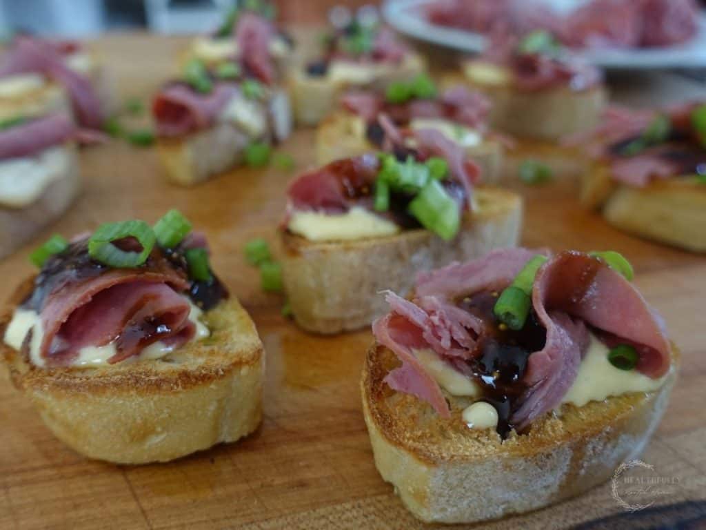 beef crostini on a wooden cutting board scattered about
