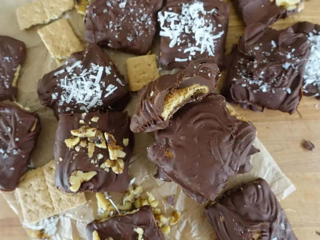 peanut butter filled chocolate covered graham cracker next to coconut topped and walnut topped chocolate dipped grahams