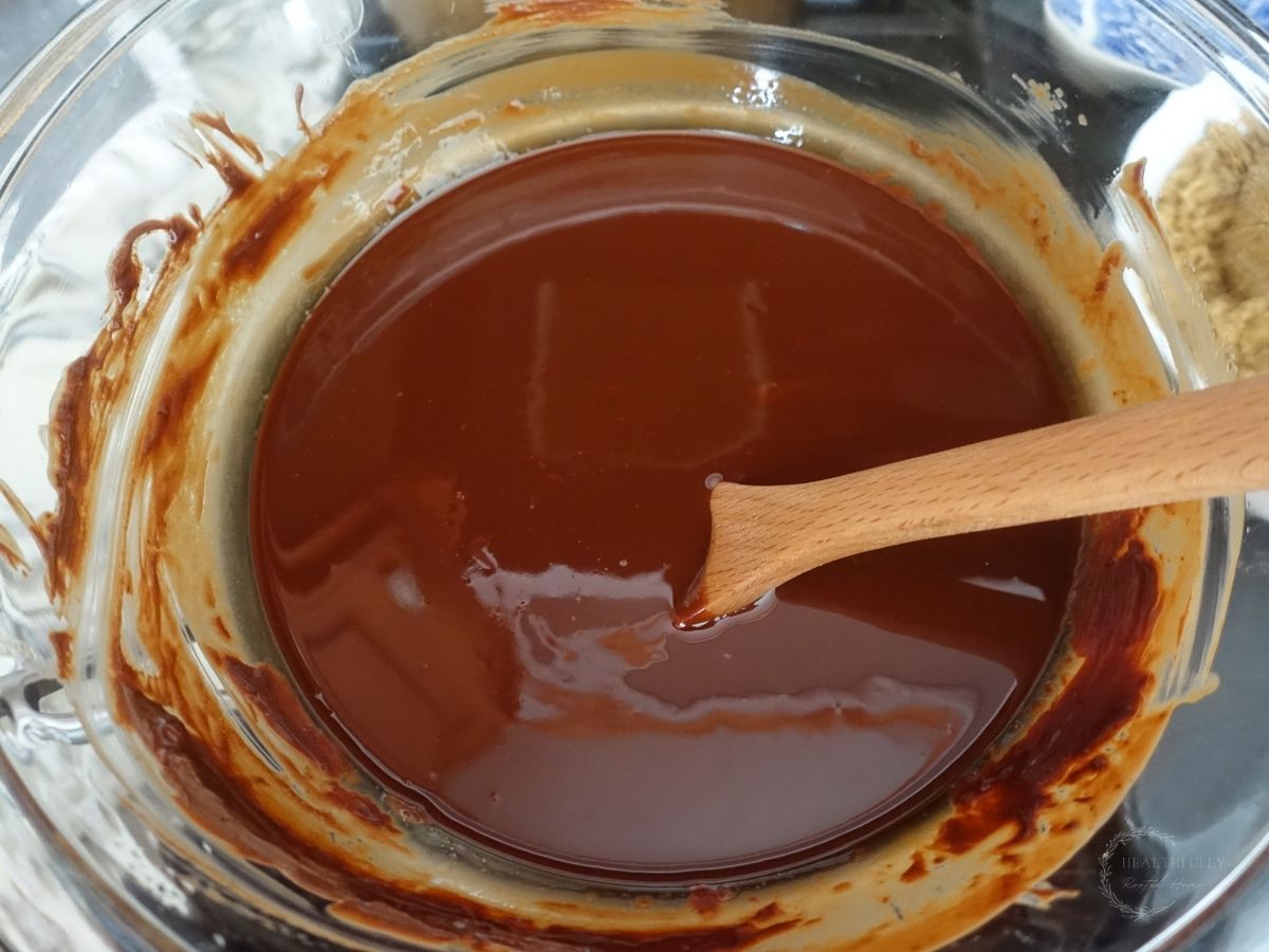 melted butter and chocolate in a double boiler with a wooden spoon sticking out