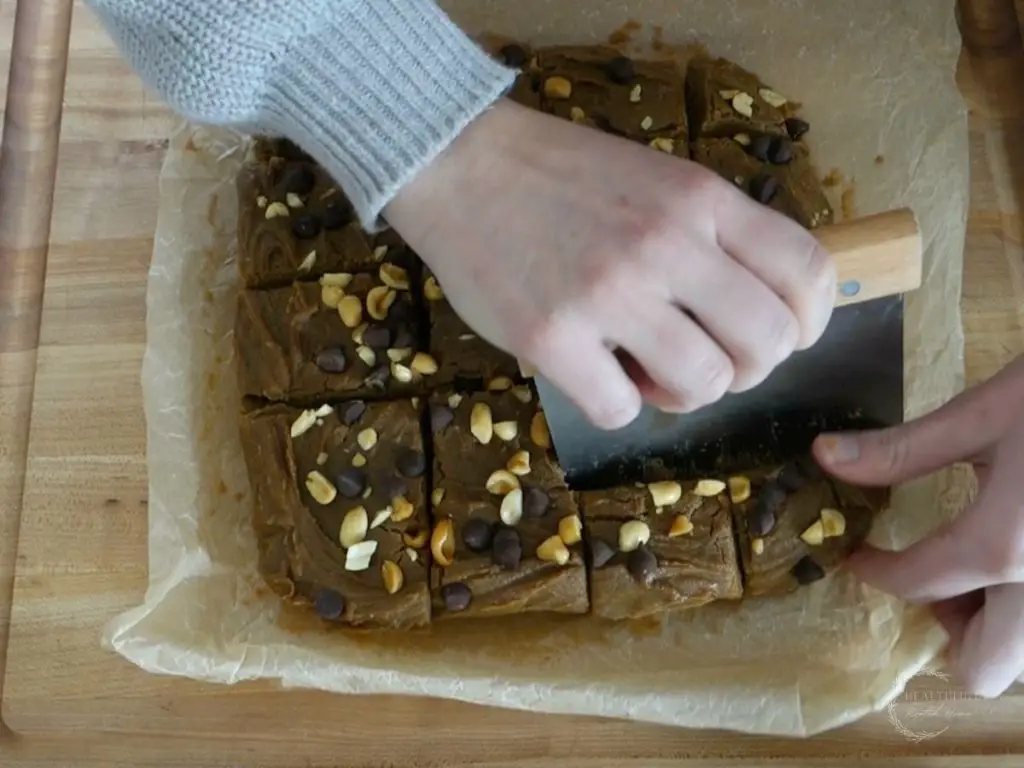 slicing no bake peanut butter fudge with a dough scraper