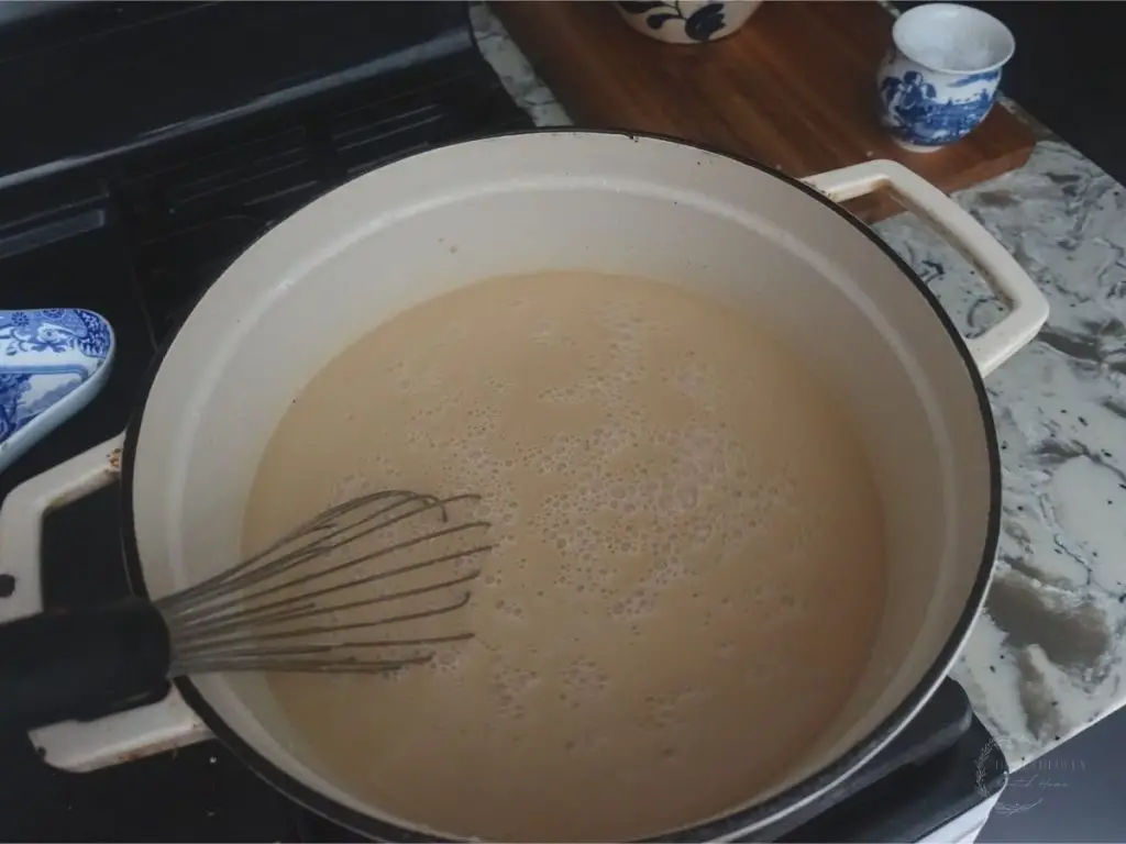 coconut sugar dissolved in whole milk in a dutch oven with a whisk inside
