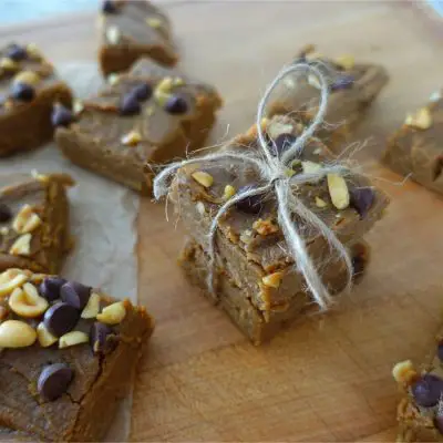 no bake peanut butter fudge pieces laying on a wooden cutting board with two pieces stacked on top eachother wrapped up with twine