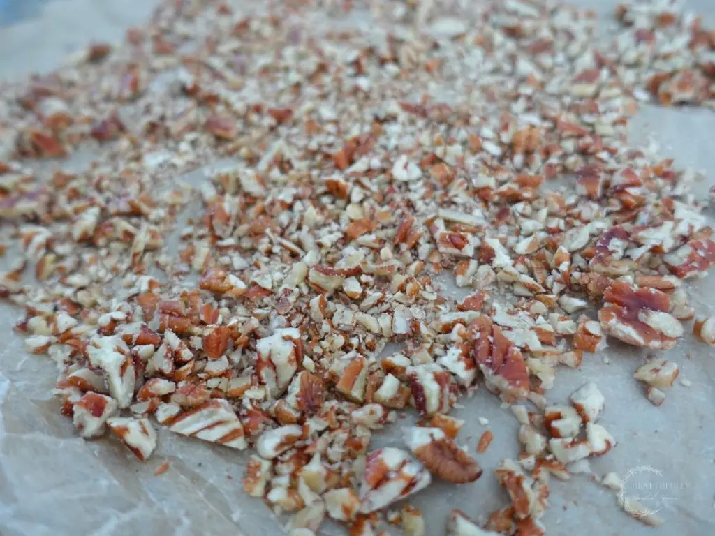 toasted pecans on a baking sheet with parchment paper