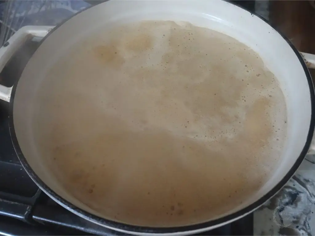 boiling milk and coconut sugar in a white dutch oven looking foamy