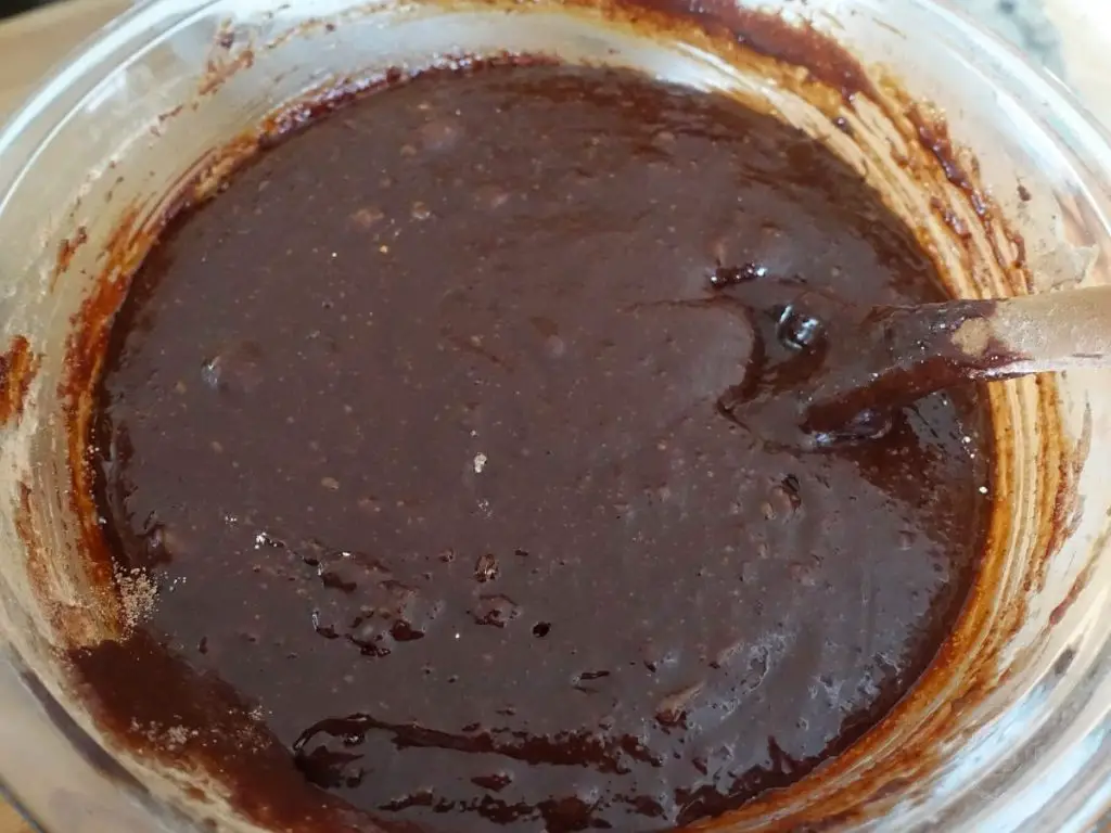brownie batter in a clear bowl with a spoon sticking out