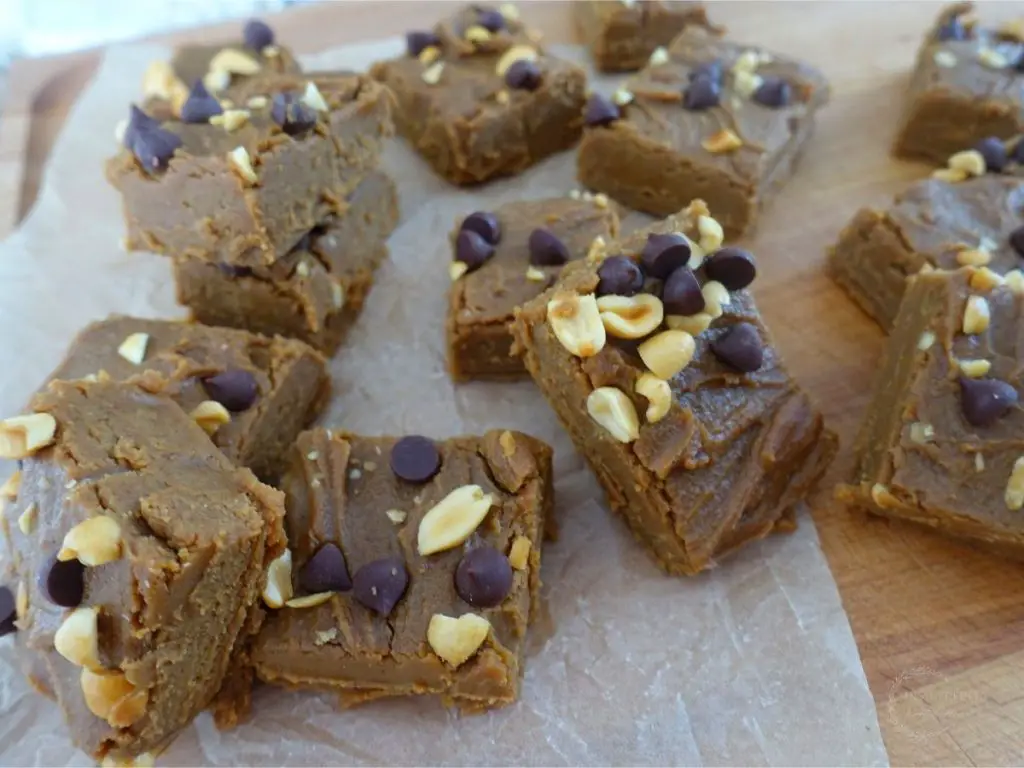 no bake peanut butter fudge pieces stacked on top each other overtop a piece of parchment paper