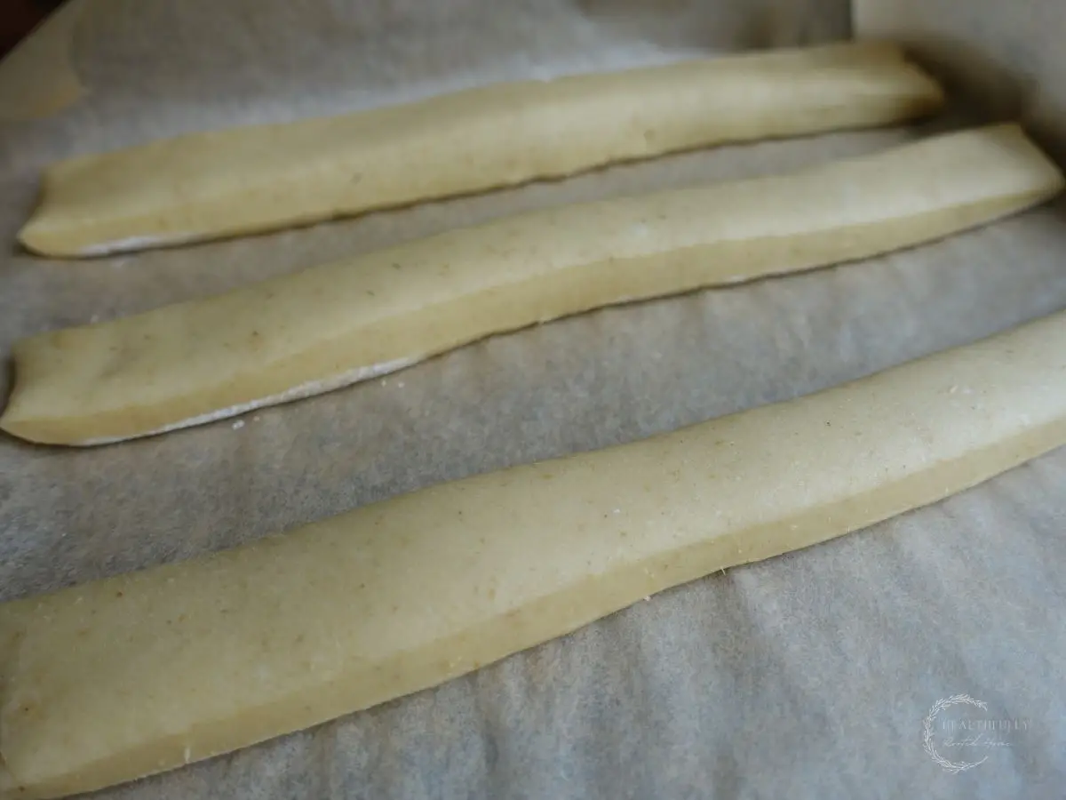 sourdough breadstick dough after proofing on a parchment lined baking sheet so you can see how poofy they are