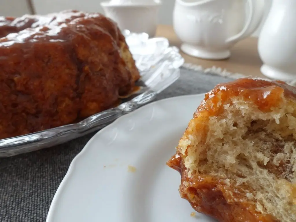 a plate of sourdough monkey bread next to the full bundt loaf with white vintage jars behind it