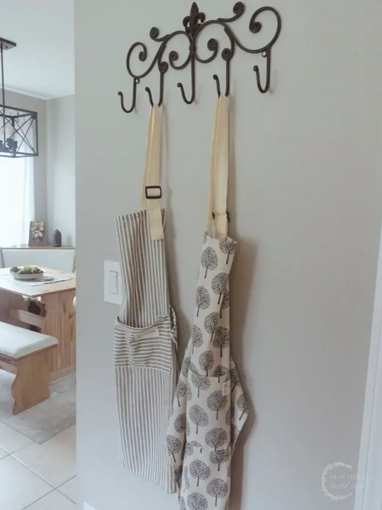 chefs aprons being used for decor hanging on an ironstone decorative hanging rack in a kitchen