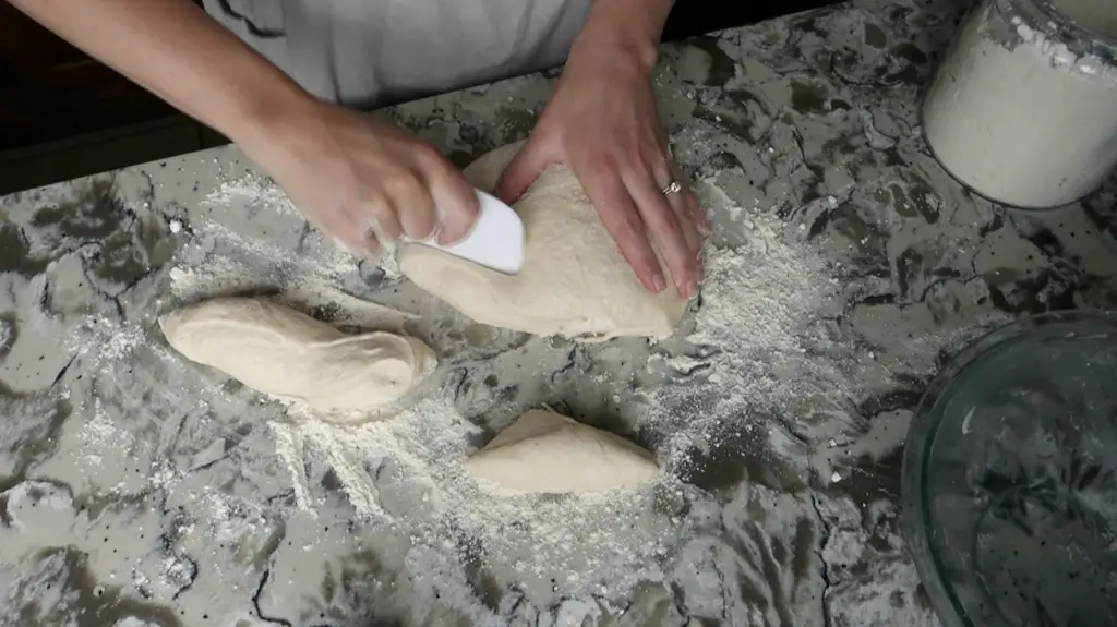 using a dough scraper to slice sourdough pretzel dough into pieces