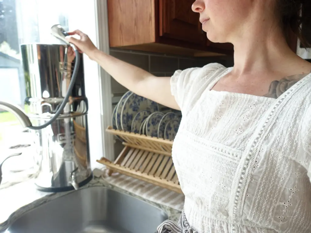 kyrie with healthfully rooted home filling her berkey water filter using the hose from the kitchen sink