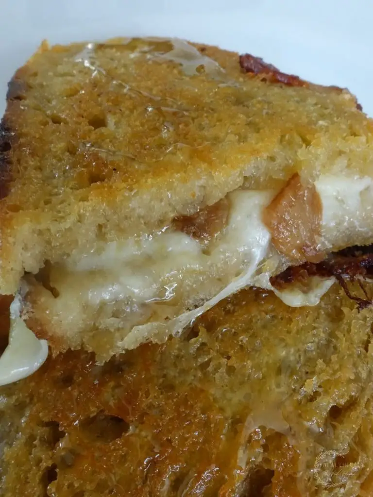 provolone grilled cheese sandwich cut in half and stacked on top the other half so you can see the melted cheese and garlic confit on the inside