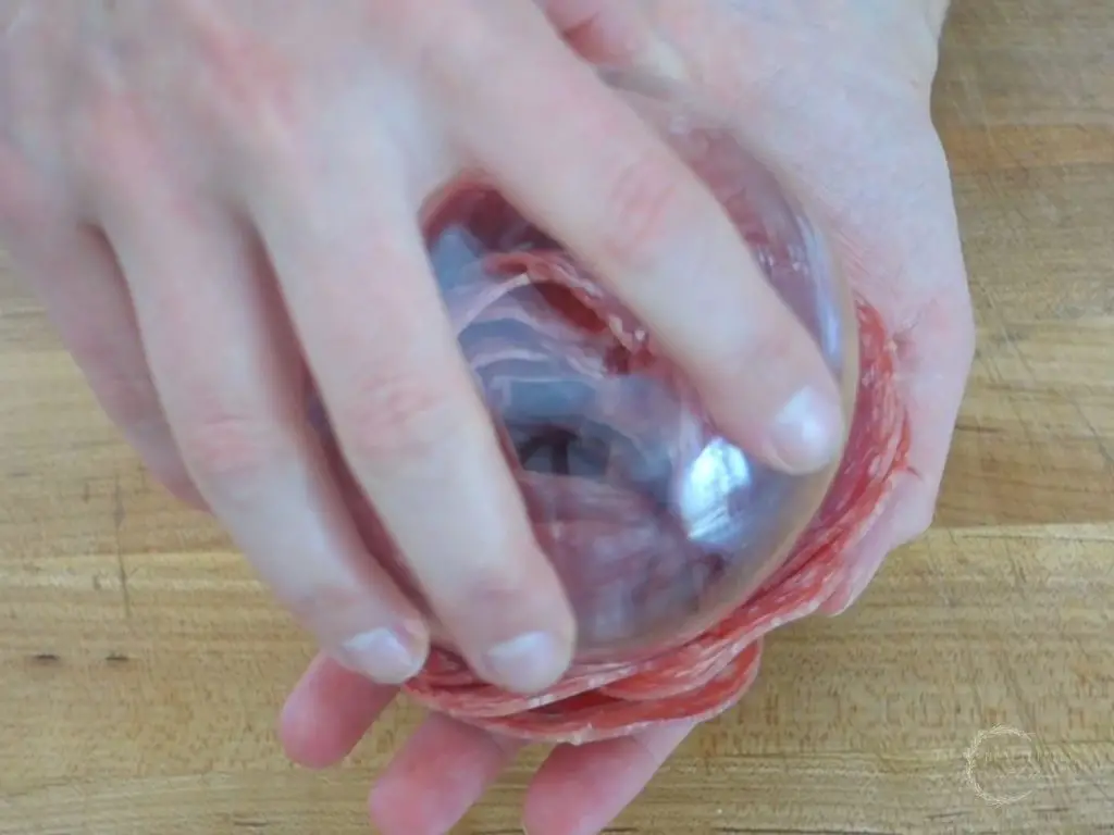 slightly twisting the glass that the salami is on to remove the salami rose