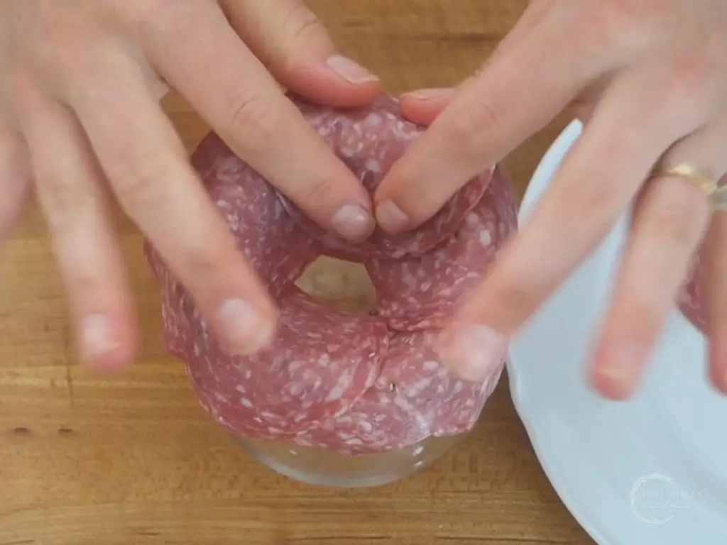 placing another layer of salami on a glass to make a fuller looking salami rose