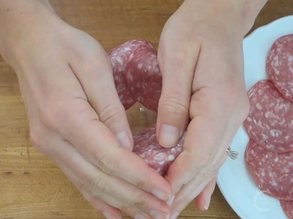 cusping the salami on top of the rim of a glass to make a tighter salami rose