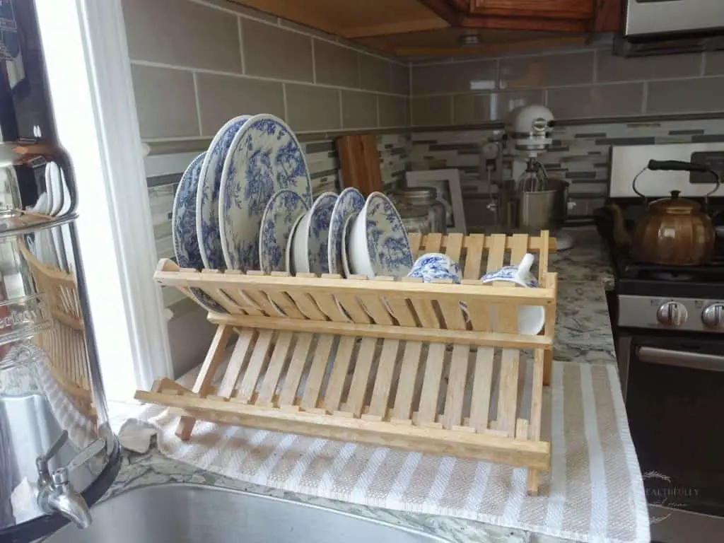 dish drying rack and blue and white dishes drying on it with a berkey water filter and a copper tea kettle and a white kitchen aid stand mixer in a kitchen highlighting some kitchen essentials for a new home