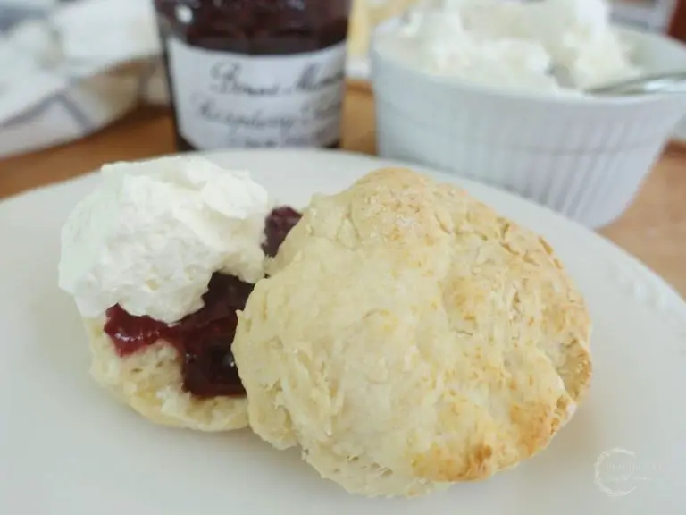 lemonade scones no cream with homemade whipped cream and jam on a white plate with the jam and cream jar in background