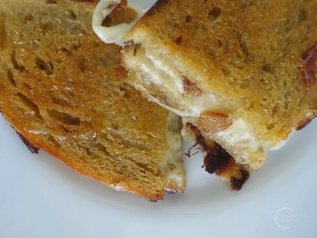provolone grilled cheese sandwich with cheese melting out and garlic confit peaking out