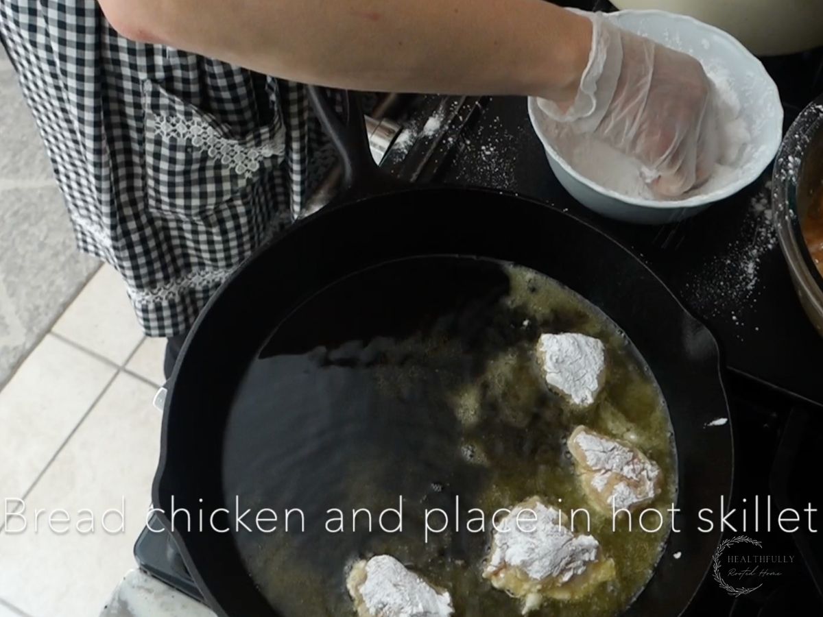 adding battered chicken to a hot cast iron skillet using gloves