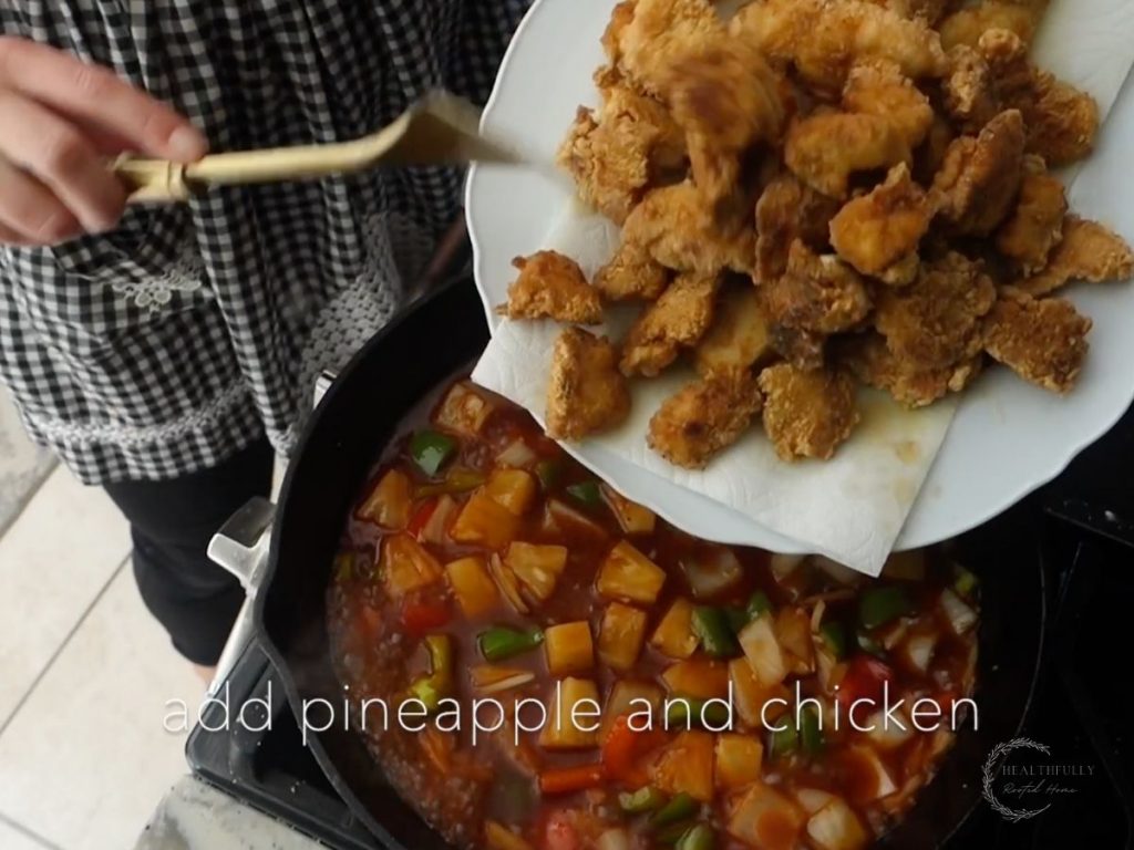 tossing in fried chicken into the sweet and sour sauce vegetables 