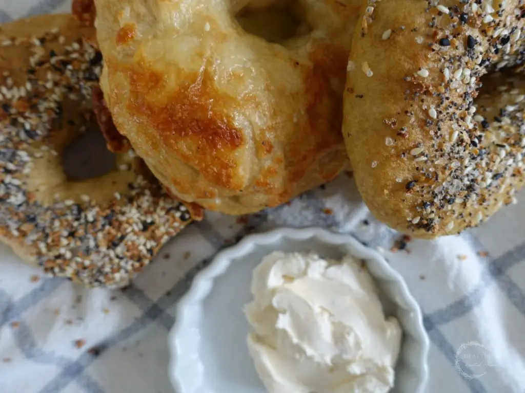 sourdough discard bagels leaning on eachother with a bowl of cream cheese next to them