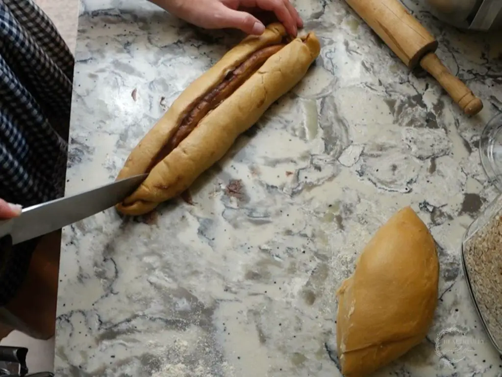 using a sharp knife to cut down the middle of the babka loaf