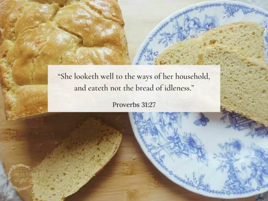 a biblical homemaking verse from proverbs overtop a scene of a homemade loaf od sourdough bread with two slices on a blue and white plate