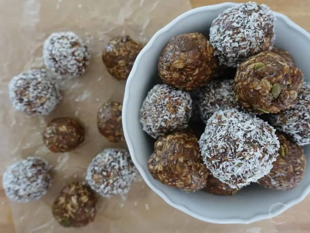 boobie balls stacked on top of eachother in a bowl with some on the outside of the bowl on top of parchment paper
