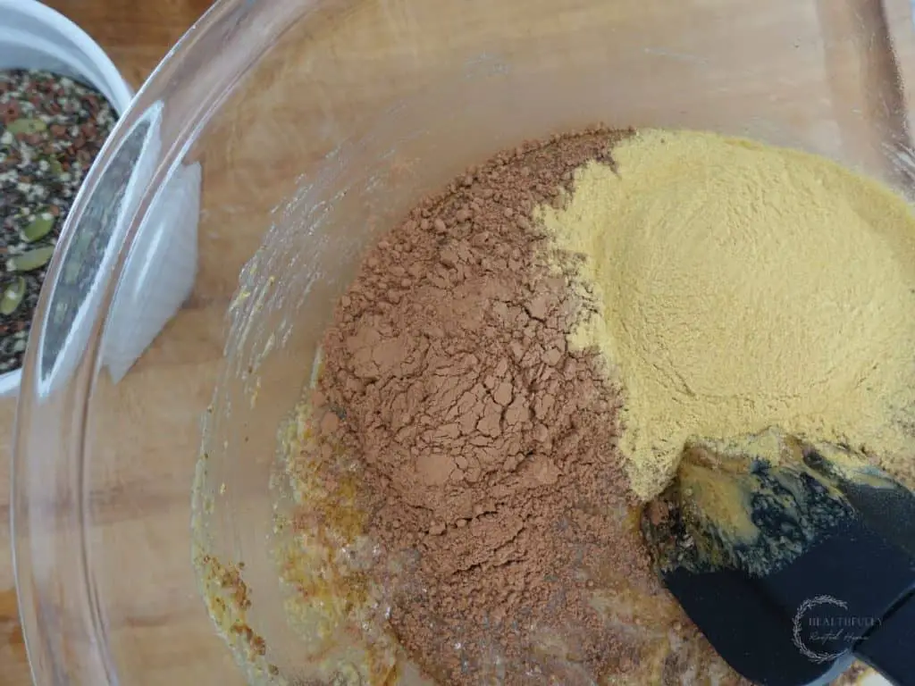 cacao powder and brewer's yeast in a glass bowl about to be mixed to make boobie balls