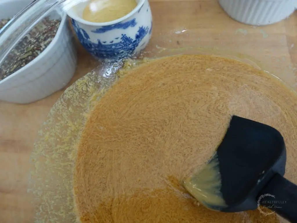 maple syrup and peanut butter mixed together in a glass bowl with a spatula resting inside