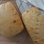 fermented bread loaves on a wire cooling rack with a striped tea towel underneath