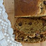 sourdough discard banana bread on a wooden cutting board with a lace doily next to it