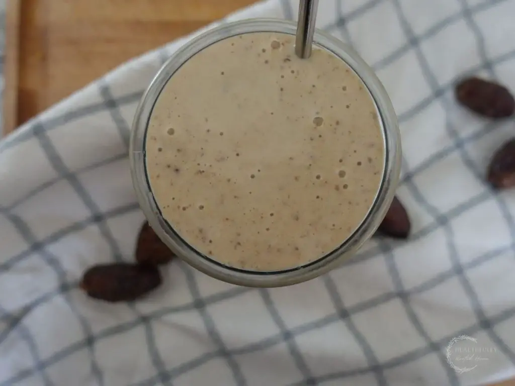 top view of a dates milkshake on a blue and white tea towel with dates surrounding it