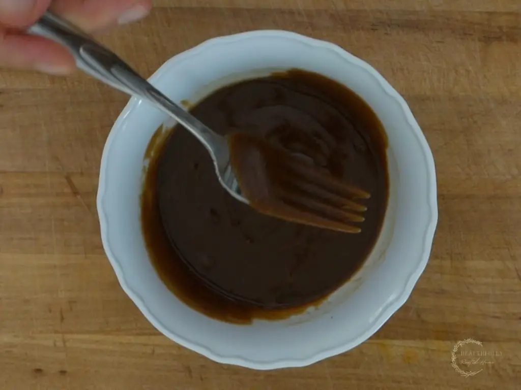 hoisin peanut sauce mixed up with a fork in a white bowl showing how easy the recipe is to make