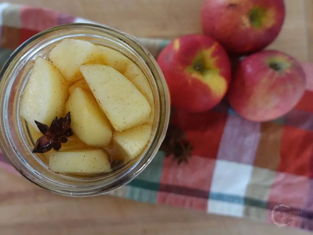 fermented apples with star anise and cinnamon in a mason jar with apples on the side