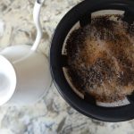 gooseneck kettle next to a hand drip coffee maker with coffee and water dripping through to make pour over coffee