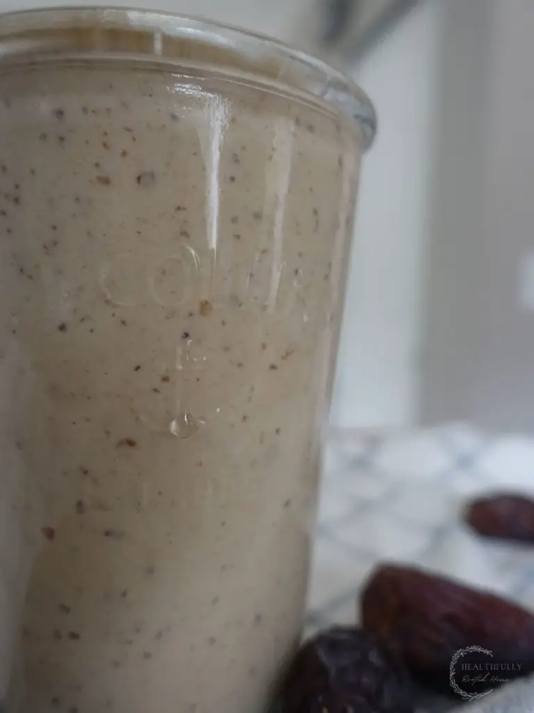 dates milkshake in a drinking glass with a straw and dates surrounding 