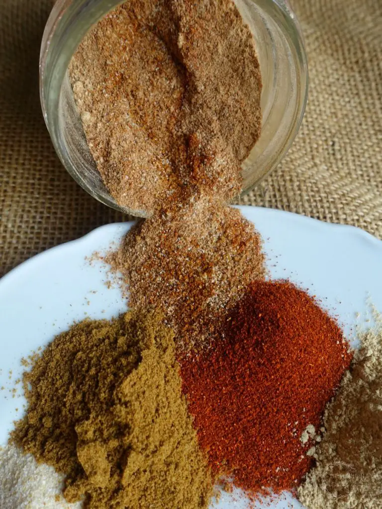 low sodium taco seasoning in a jar tipped over and spilling onto a plate of spices used to make low sodium taco seasoning