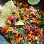 mexican caviar in a large bowl with a tortilla chip dipped inside