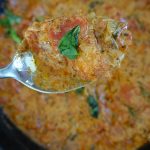 tomato mascarpone sauce in a cast iron skillet with a spoonful of sauce close up and a piece of basil on top