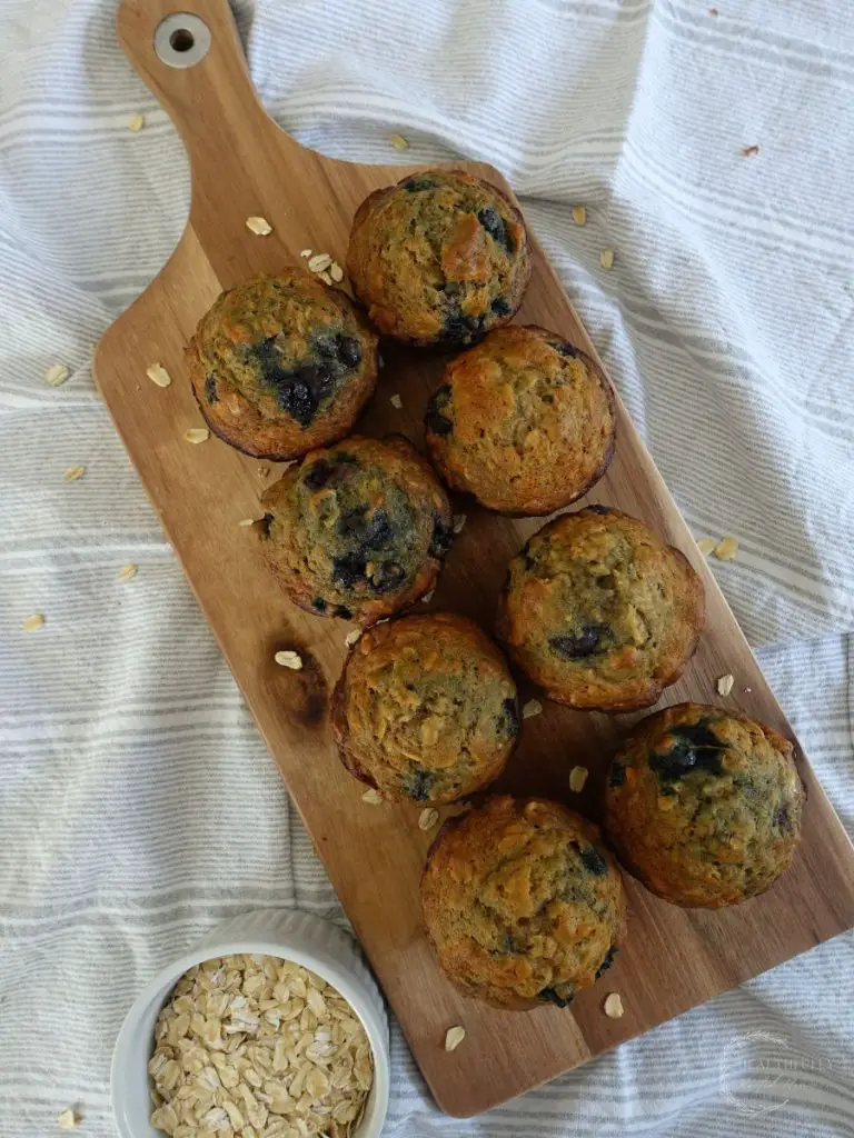 wooden serving tray with a batch of banana blueberry oatmeal muffins 