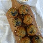 banana blueberry oatmeal muffins lined up on a serving board with a bowl of oats next to it