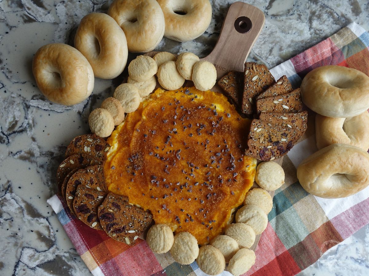 pumpkin butter board with bagels crackers and cookies surrounding it