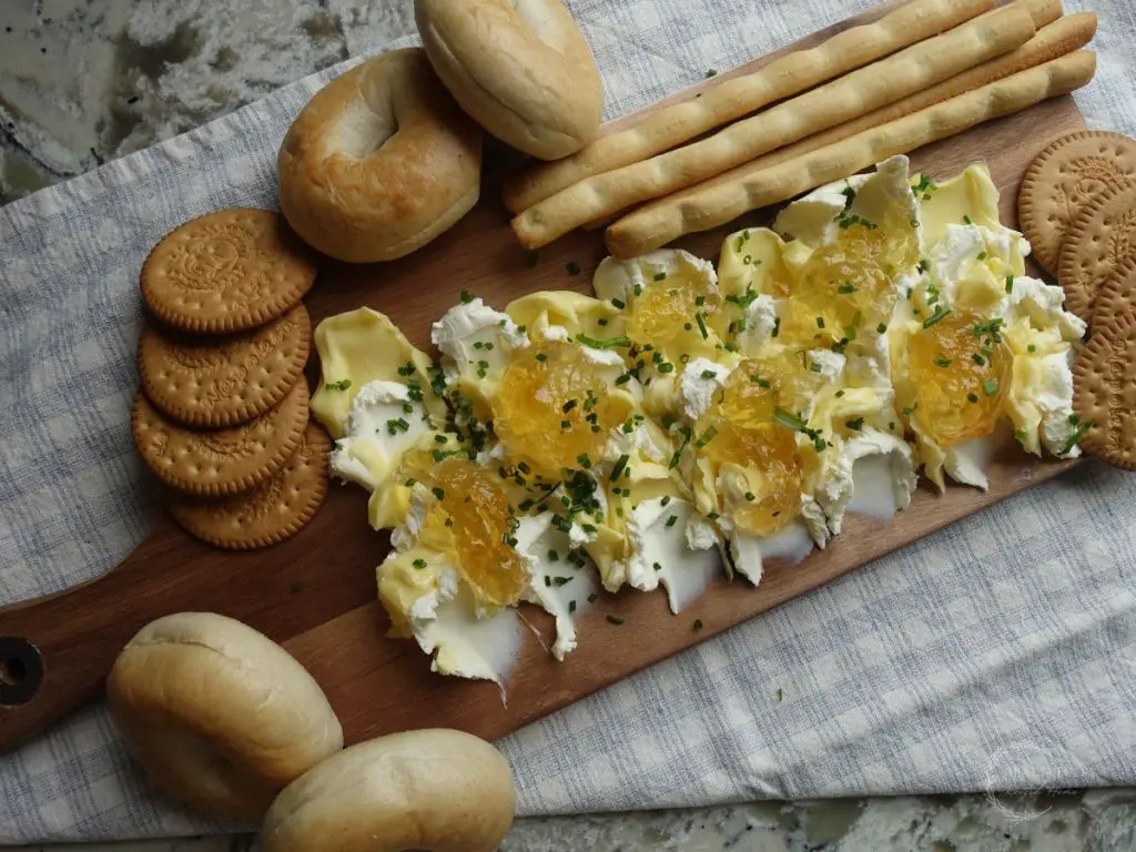 pepper jelly butter board with crackers and bagels served on a serving platter