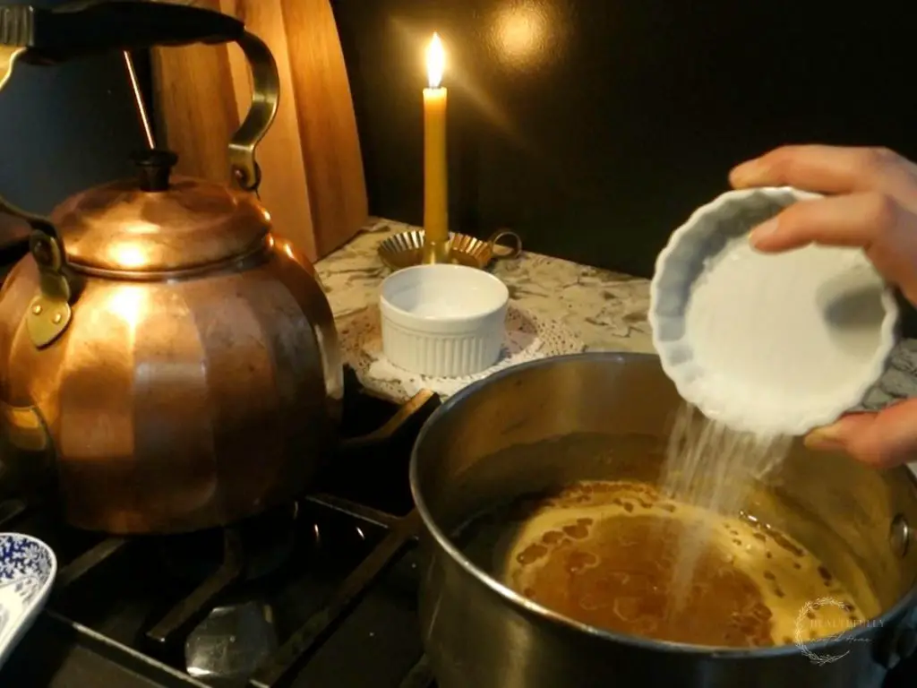pouring sea salt into the caramel sauce to make salted caramel sauce
